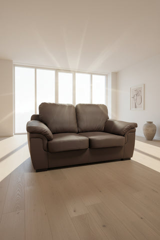 Brown leather sofa in a showroom with tiled floor and wall art.